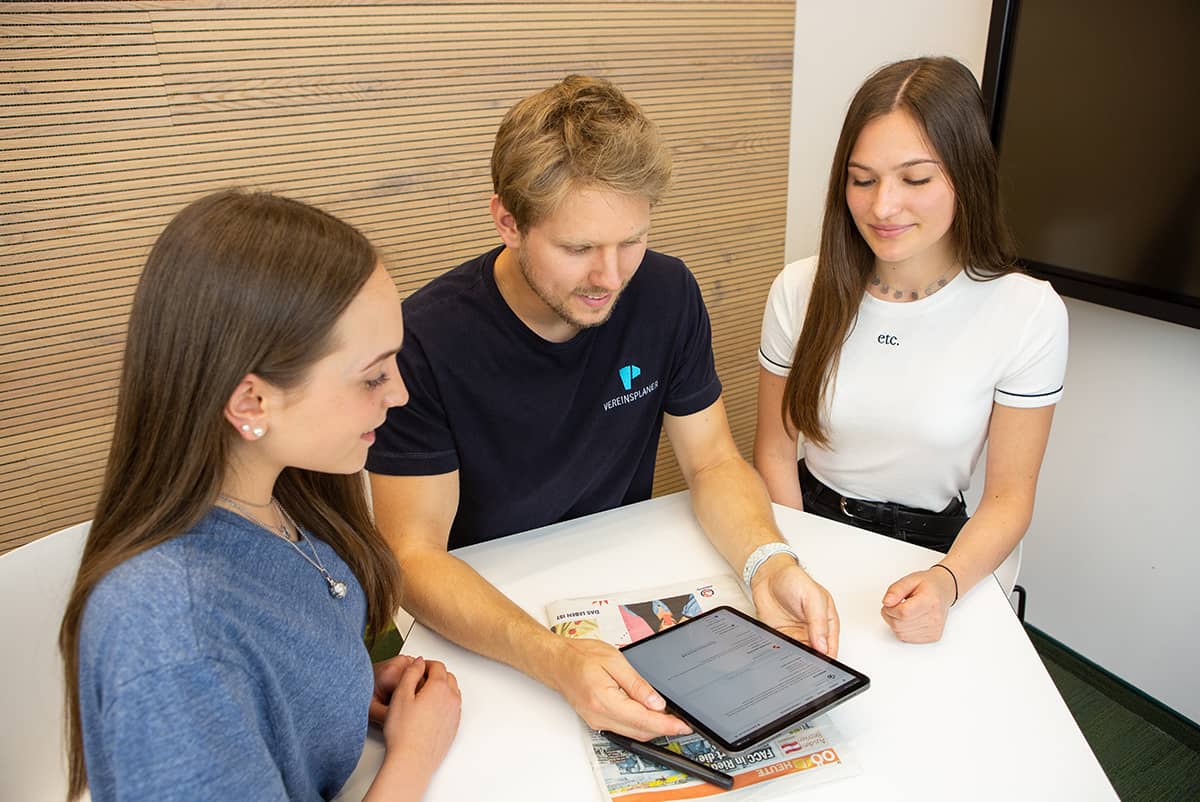 Personen im Verein lesen ihre News über ein Tablet