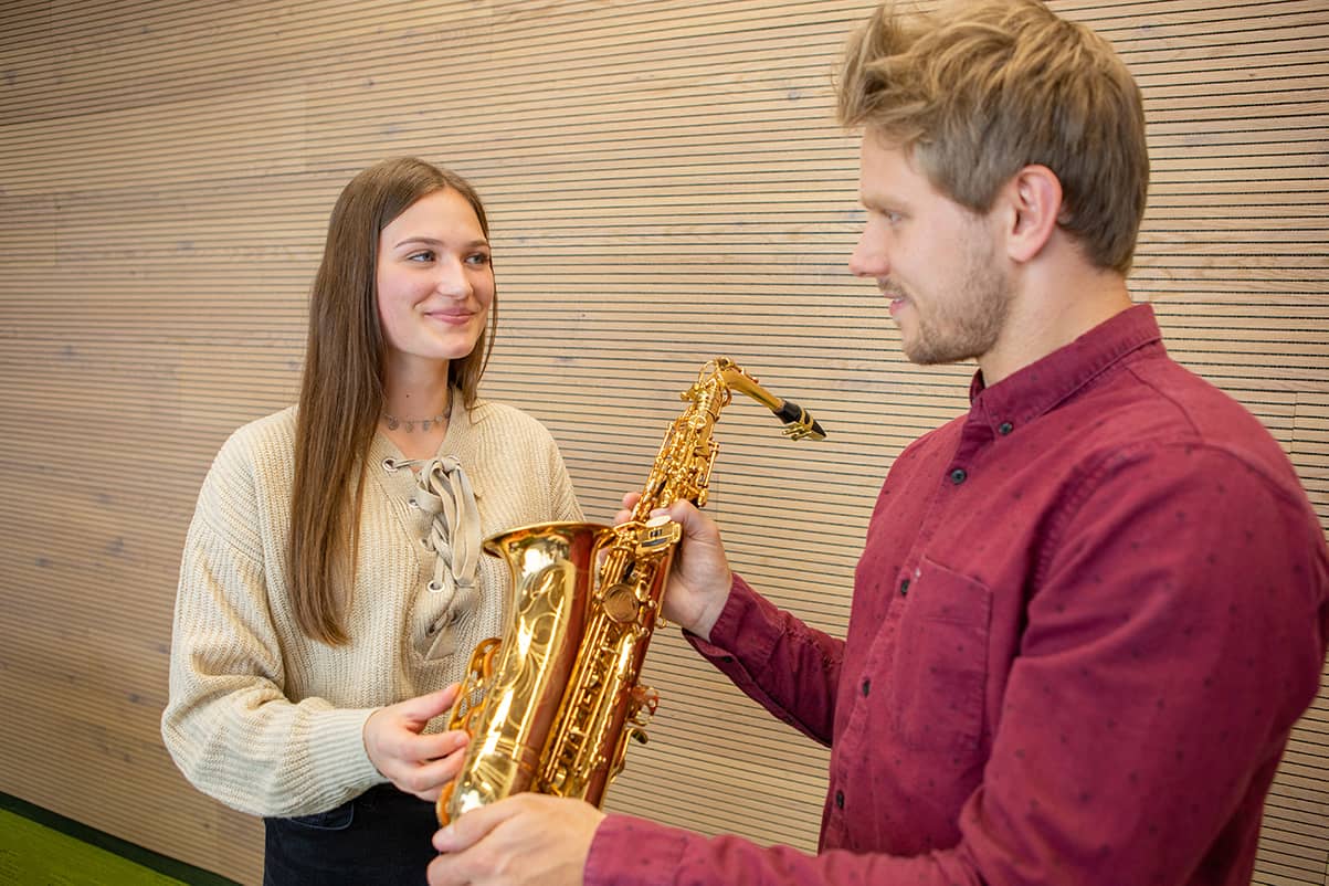 Mann übergibt Jugendlicher Musikinstrument